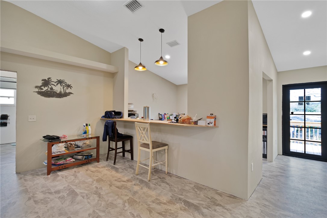 Bar featuring vaulted ceiling, pendant lighting, and light countertops