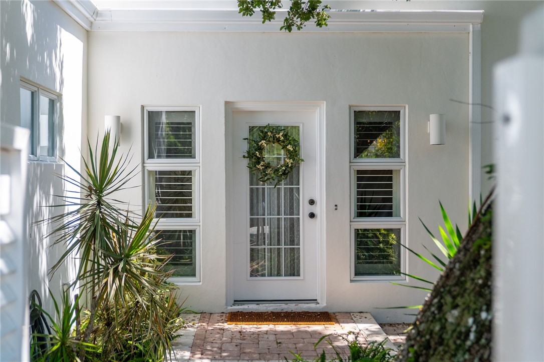 White stucco exterior with a glass-paneled entry door and coordinating sidelite windows