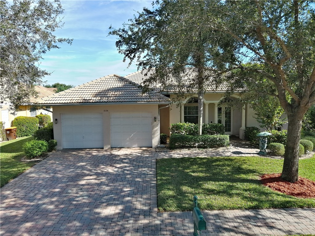 Stucco exterior featuring a tiled roof and an arched entry