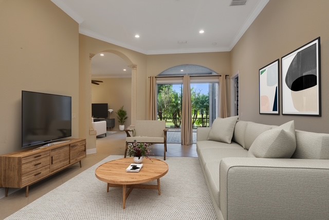 Spacious Virtual Staged living area featuring neutral wall tones, recessed lighting, crown molding, and large glass sliding doors opening to the exterior