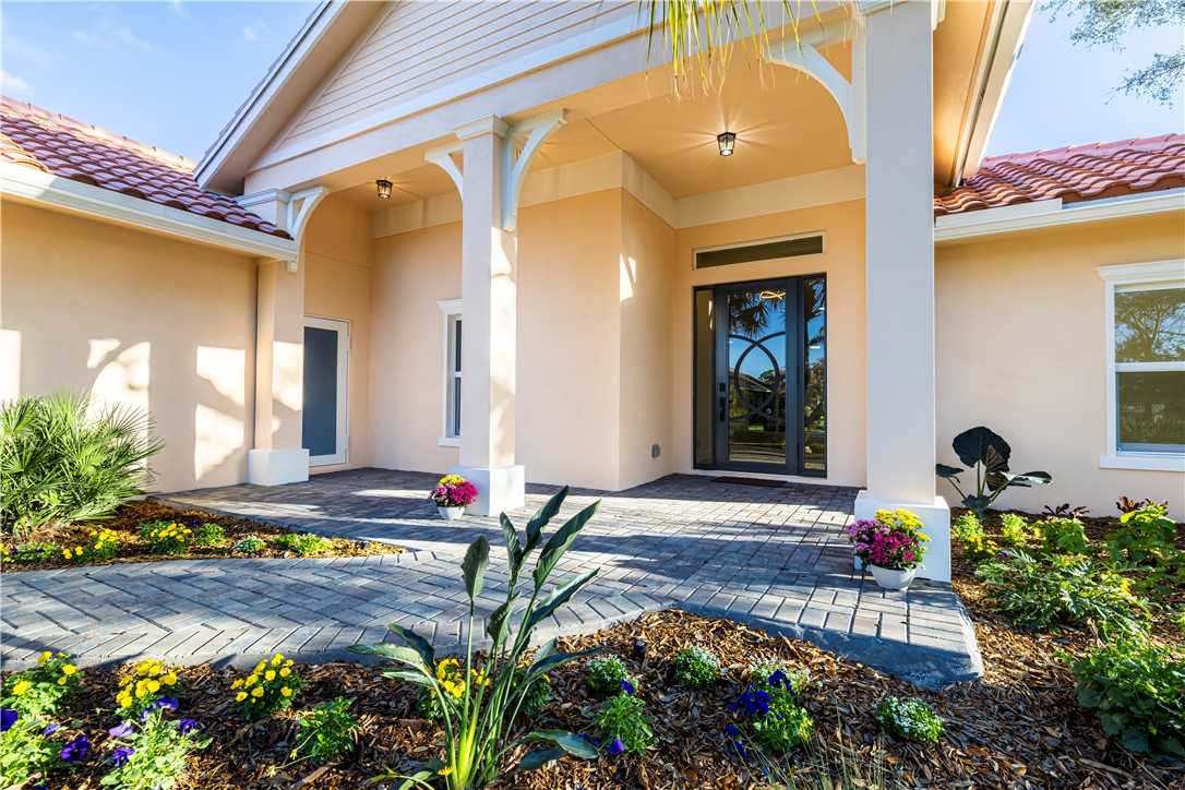 Stucco exterior featuring a tiled roof and a covered entry with columns and archways