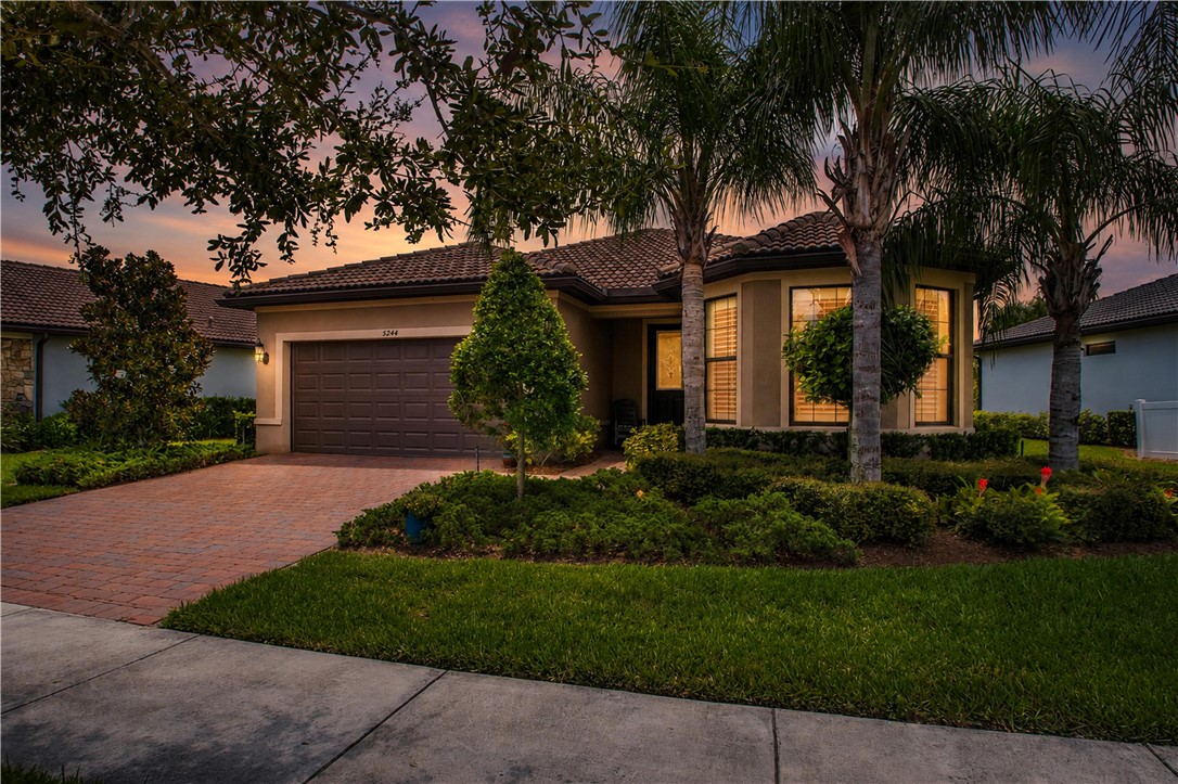 Single-story residence featuring a tile roof, an integrated garage, and a paver driveway