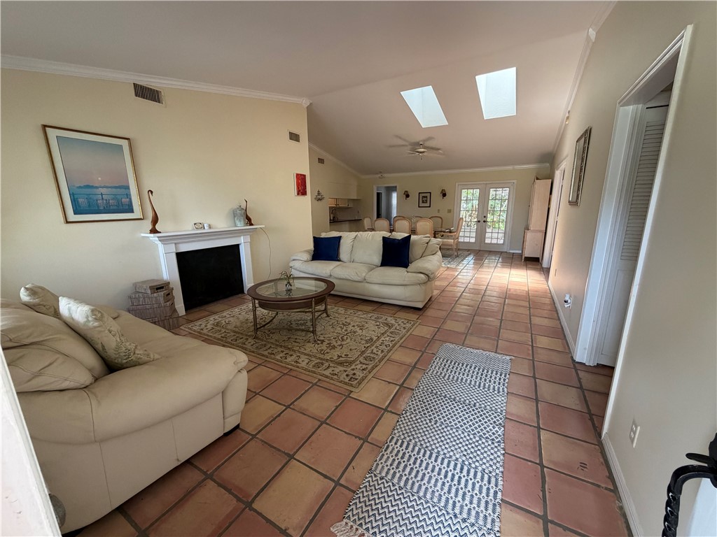 Spacious living area featuring terra cotta style tile flooring, a fireplace with a white mantel, and vaulted ceilings