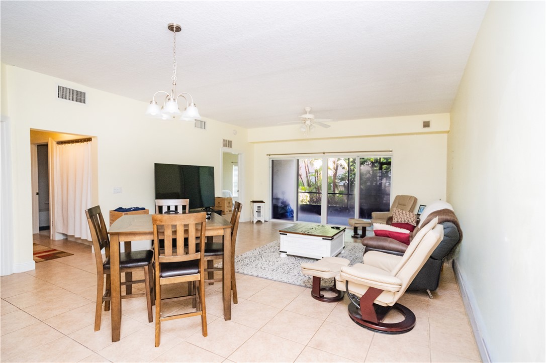 Open-concept living area featuring tile flooring, a multi-light chandelier, sliding glass doors to the exterior, and ceiling-mounted air conditioning vents