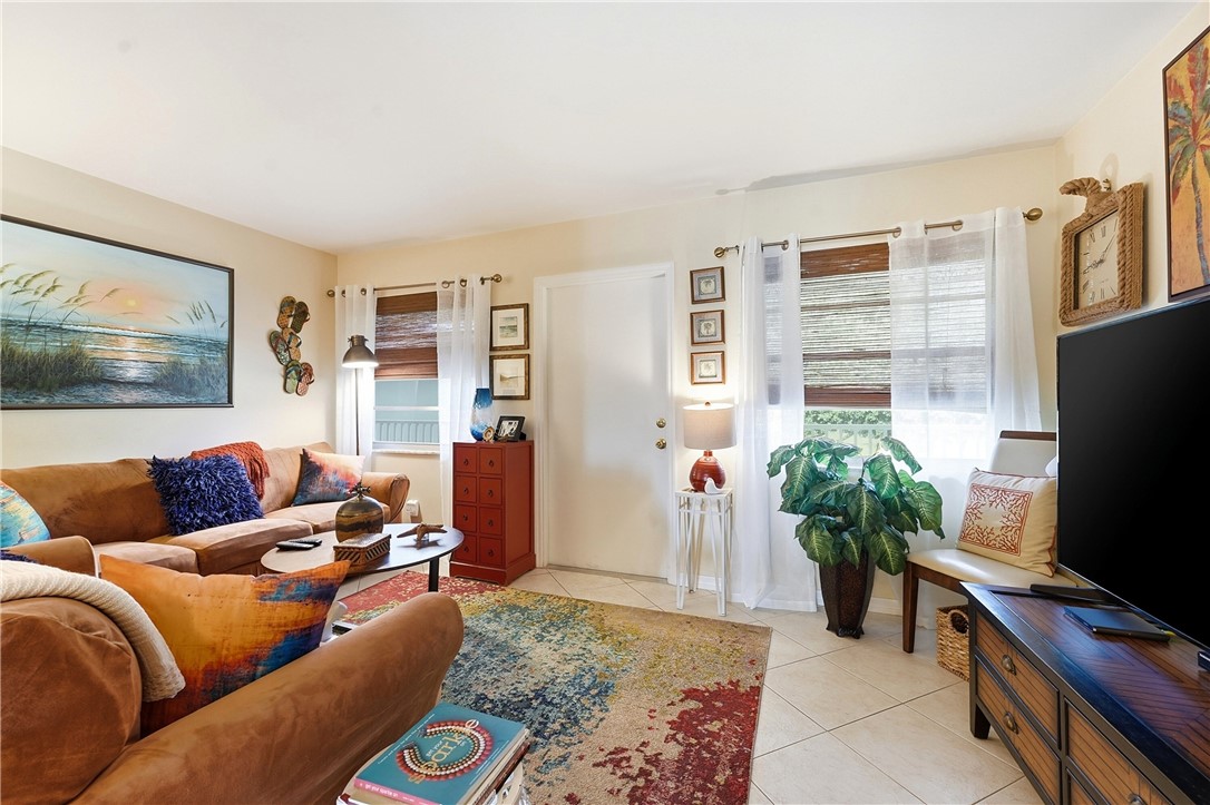 Living area featuring light-toned walls, tile flooring, and multiple windows