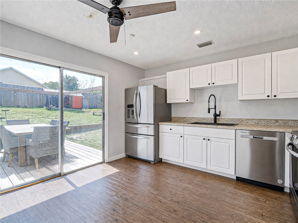 Kitchen featuring stainless steel appliances, white cabinetry with dark hardware, a black sink with a matte black faucet, and wood-finish flooring