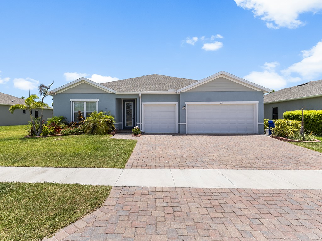 Single-story residence featuring a two-car garage, brick paver driveway, and stucco exterior