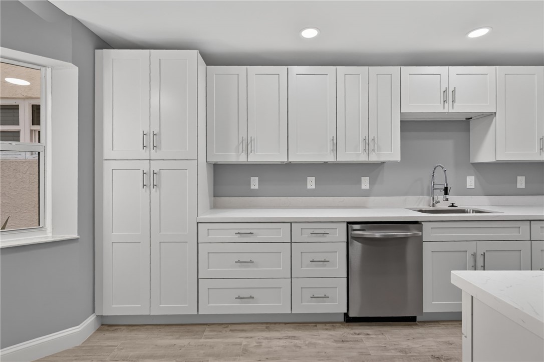 Modern kitchen featuring white shaker-style cabinetry, light wood-finish flooring, and recessed ceiling lighting