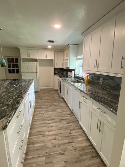 Kitchen featuring white shaker-style cabinetry with brushed nickel hardware, granite countertops, and wood-finish flooring