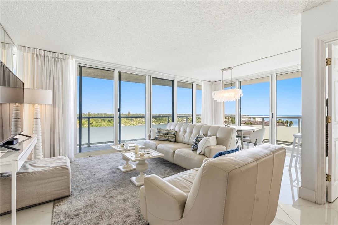 Spacious living area featuring floor-to-ceiling sliding glass doors, a private balcony, and ocean scenery