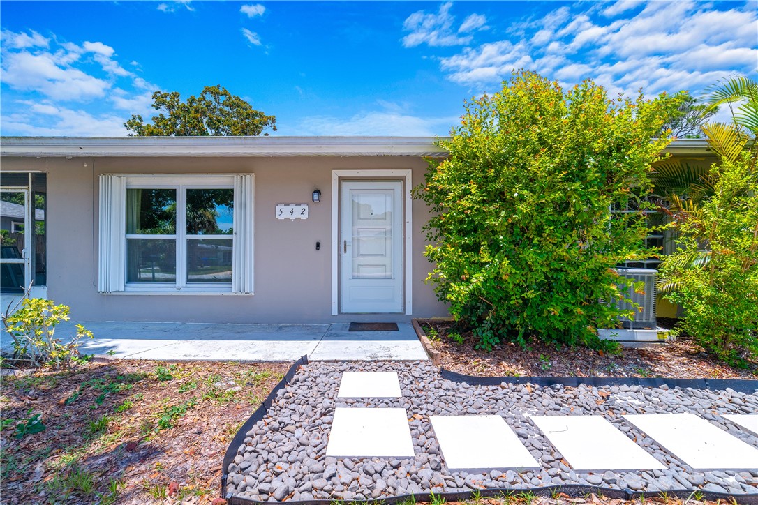 Exterior facade with a white entry door, visible house numbers, and a concrete walkway