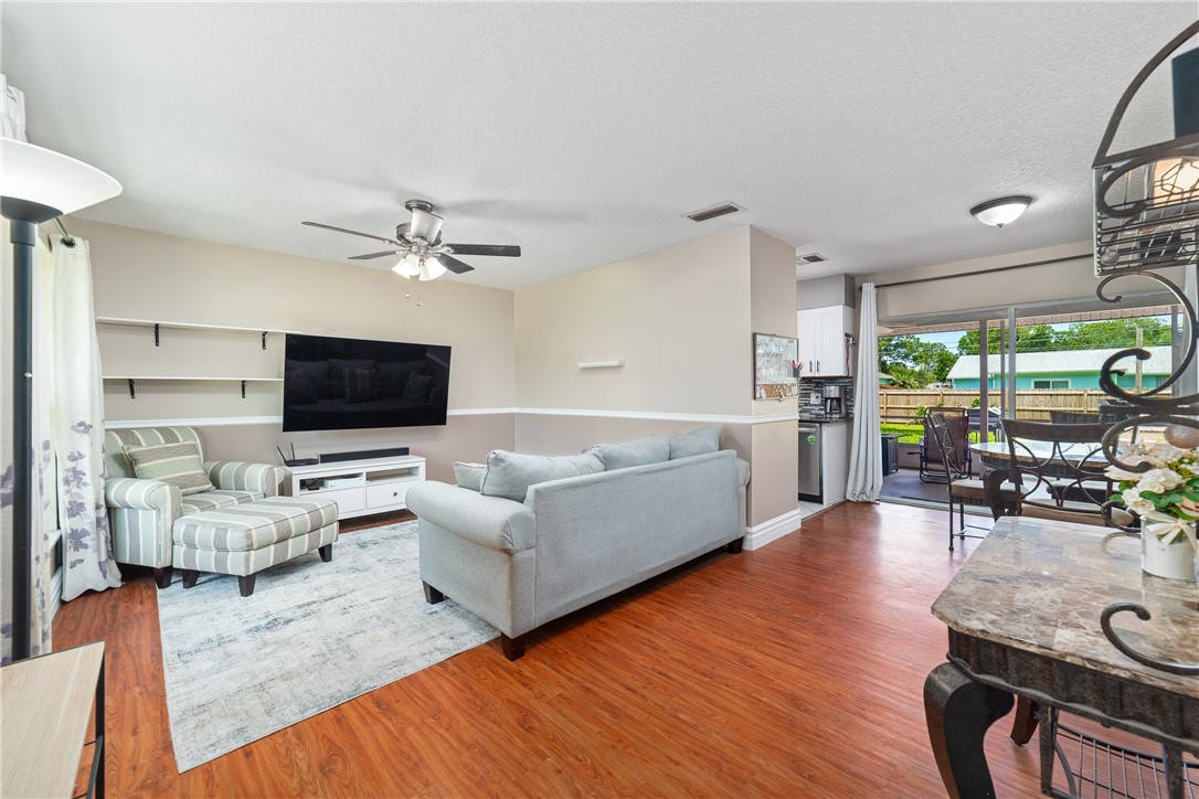 Open-concept living area with wood-finish flooring, a ceiling fan, and built-in shelving