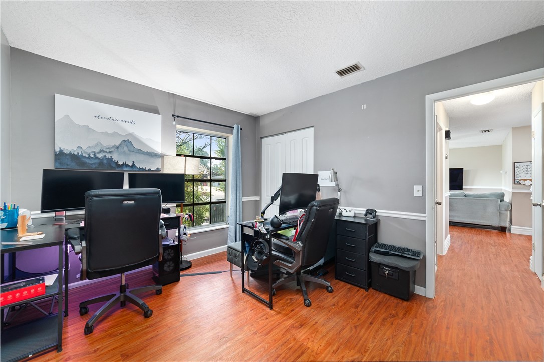 Versatile room featuring wood-finish flooring, neutral gray walls with white chair rail molding, and a window providing natural light