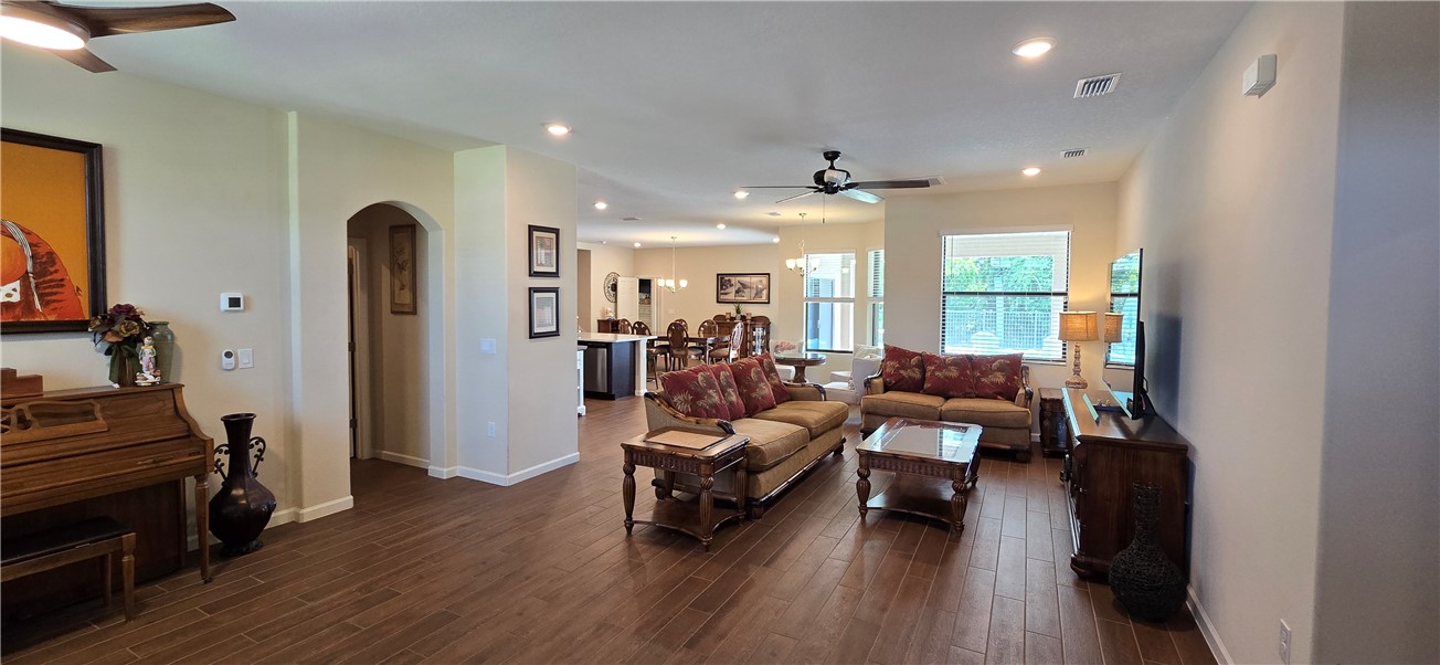 Spacious living area featuring wood-finish flooring, recessed lighting, and ceiling fans