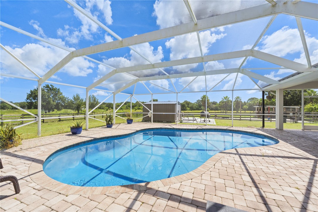 Screened enclosure featuring a freeform pool, paver deck, and extensive open-air scenery