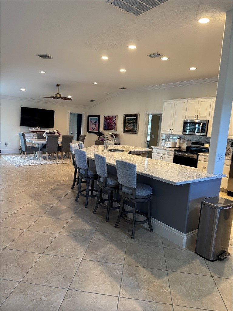 Spacious open-concept kitchen featuring a large island with stone countertops, built-in sink, and integrated breakfast bar