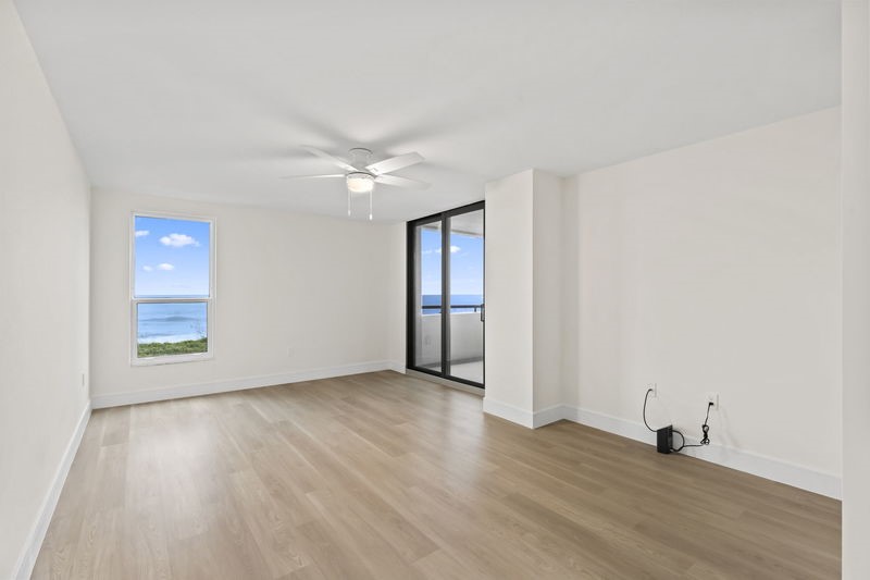 Spare room with light wood finished floors, ceiling fan, and expansive windows