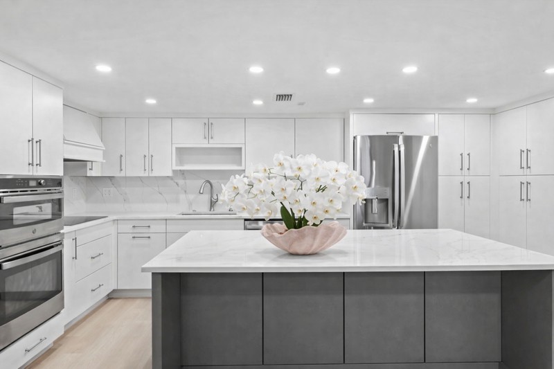 Kitchen with stainless steel appliances, gray cabinets, white cabinets, recessed lighting, and a kitchen island