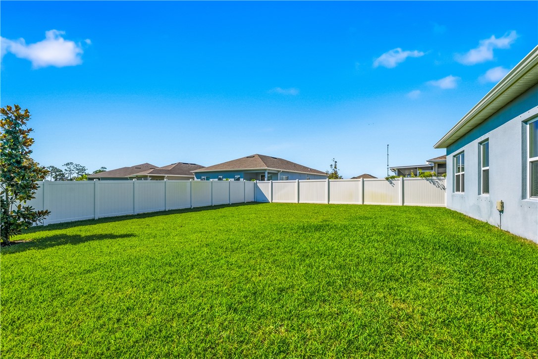 Expansive green lawn bounded by a white privacy fence