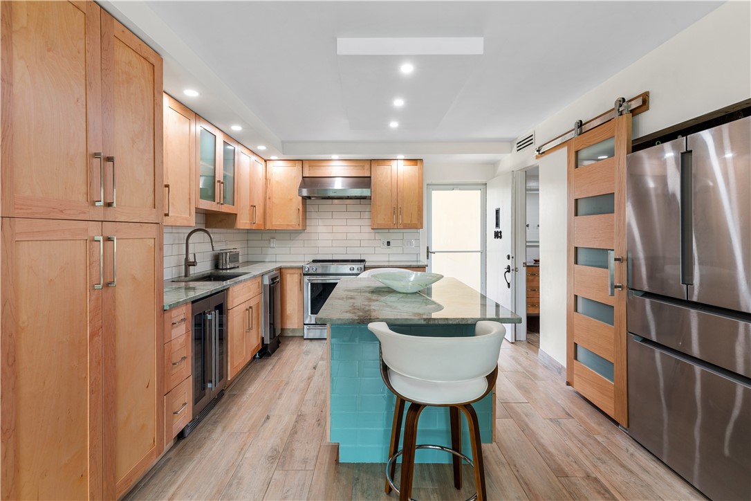 Modern kitchen featuring wood-finish cabinetry, stainless steel appliances, and a central island with a contrasting base