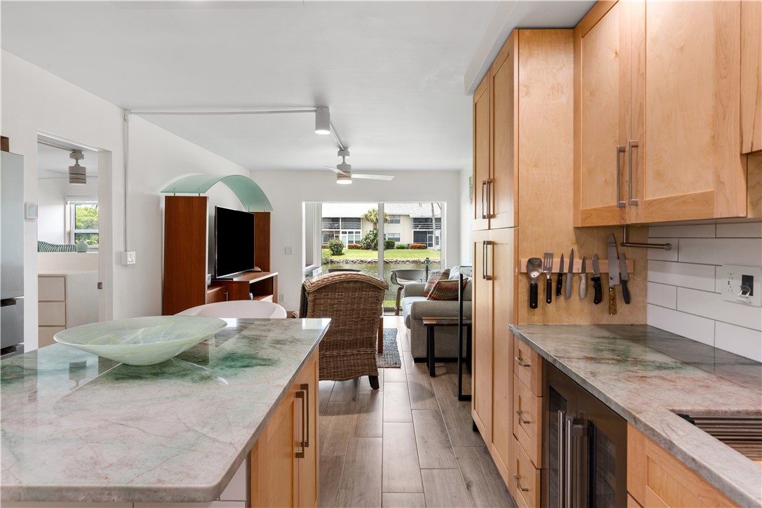 Kitchen featuring extensive light wood cabinetry, stone countertops, a subway tile backsplash, and wood-finish flooring