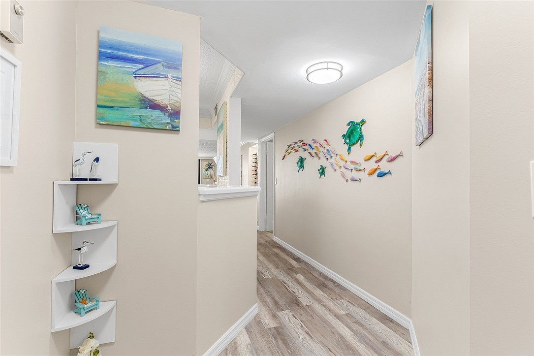 Hallway with wood-finish flooring, light neutral wall paint, and white baseboards