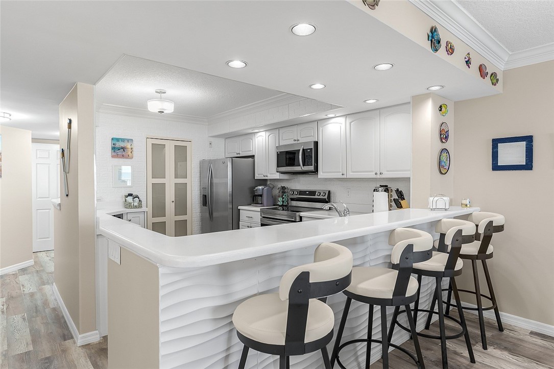 Open-concept kitchen featuring white cabinetry, stainless steel appliances, and recessed lighting
