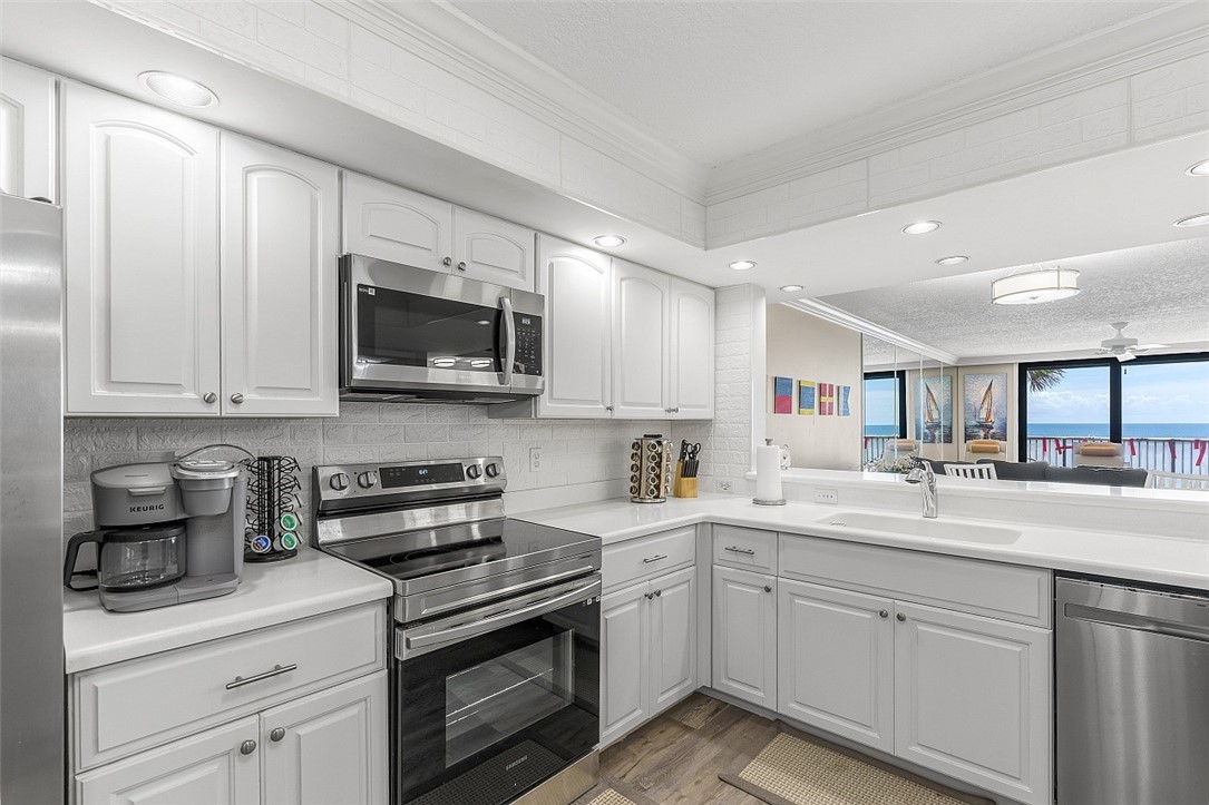 Modern kitchen featuring white cabinetry, stainless steel appliances, white countertops, and a white subway tile backsplash
