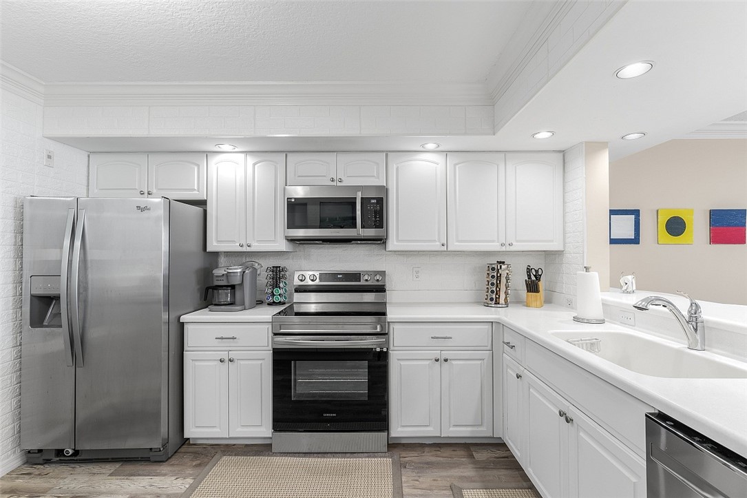Kitchen featuring white cabinetry, stainless steel appliances, a white subway tile backsplash, recessed lighting, and wood-finish flooring