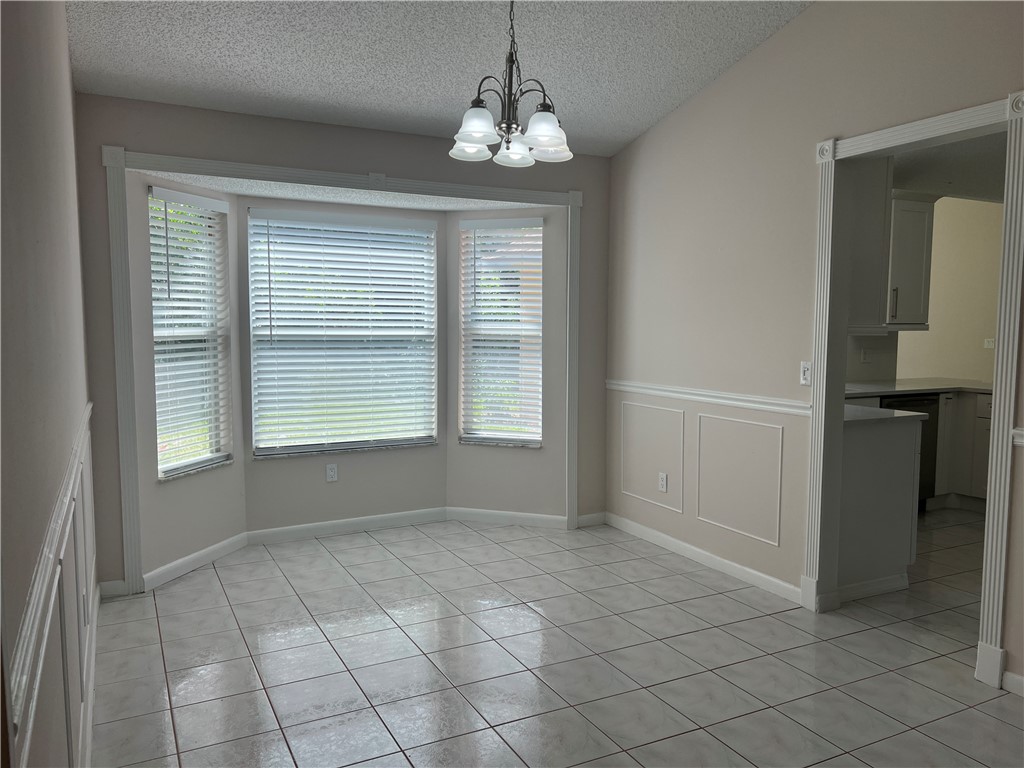 Dining area featuring a bay window, ceiling light fixture, chair rail molding, and tile flooring