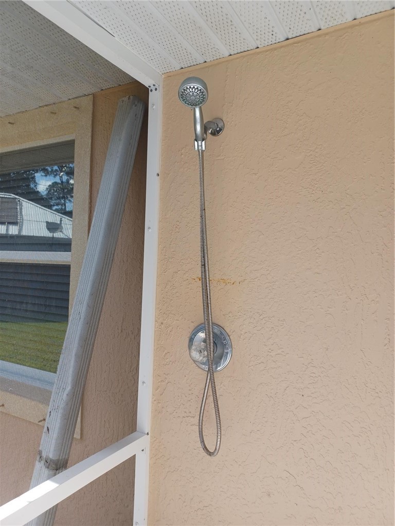Outdoor shower featuring a handheld showerhead and wall-mounted fixture