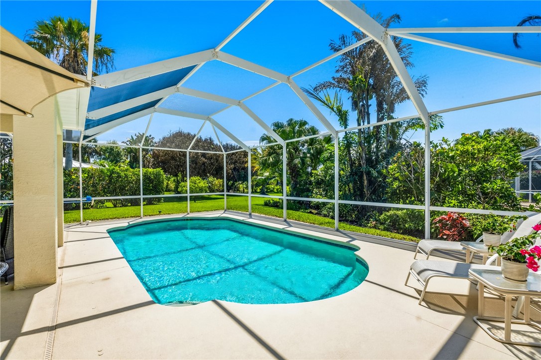 Screened-in outdoor living space featuring an in-ground swimming pool with light blue water and a surrounding concrete patio