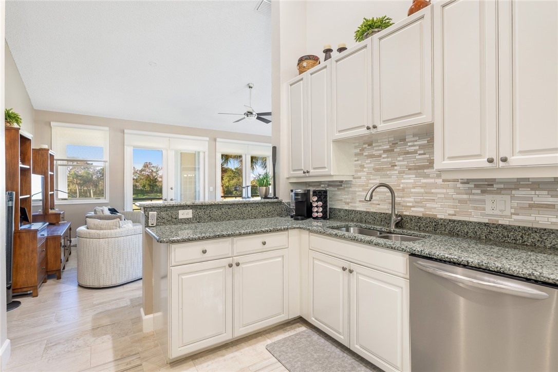 Kitchen featuring white cabinetry, a stainless steel sink, and a multi-tone tile backsplash