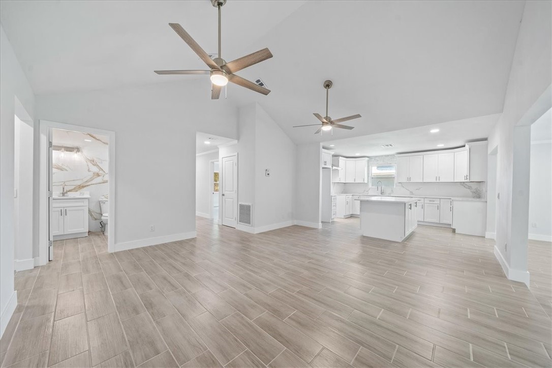 Spacious interior featuring wood-finish flooring, vaulted ceilings, and ceiling fans