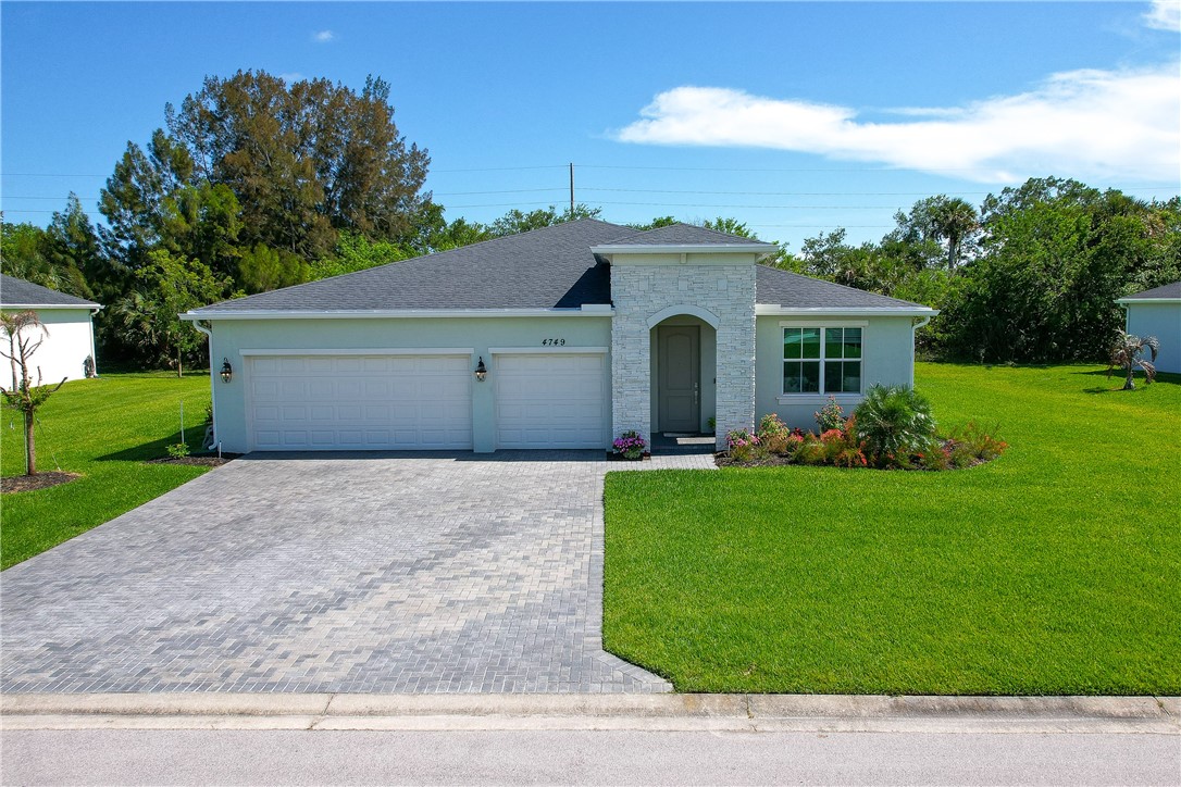 Contemporary single-story residence with a light green exterior and dark shingle roof