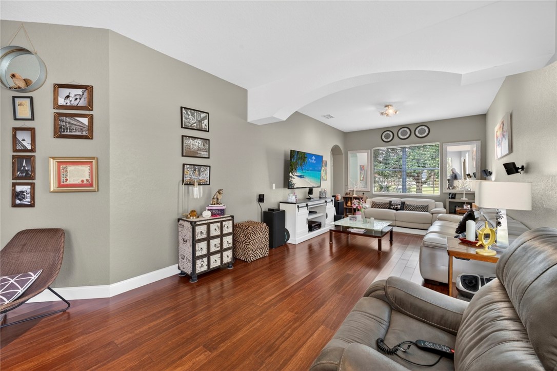 Spacious room featuring wood-finish flooring, light gray wall paint, and a tray ceiling