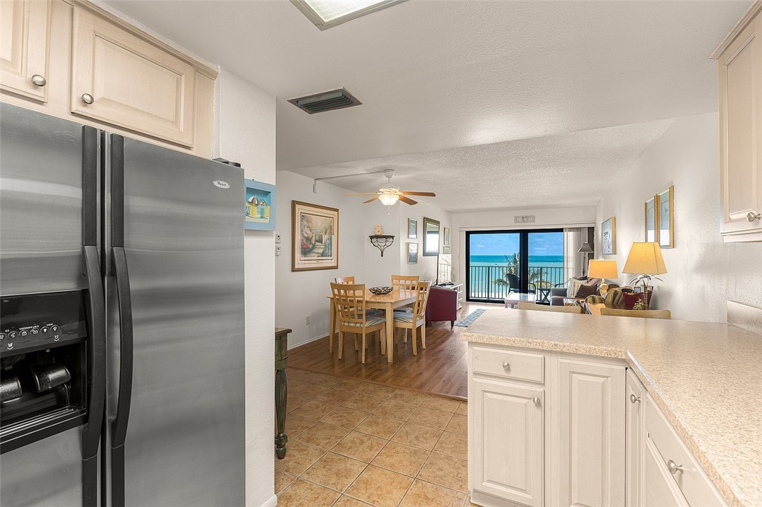 Kitchen featuring light-toned cabinetry, light-toned countertops, and a stainless steel refrigerator, with an open layout towards dining and living areas