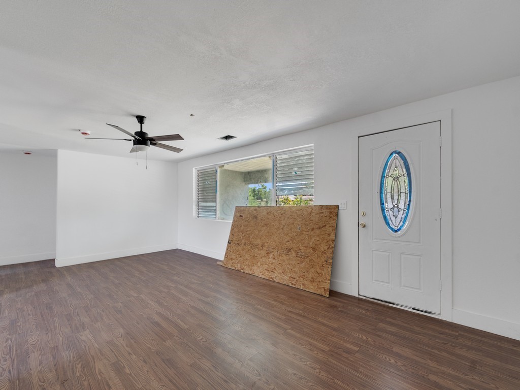 Open-concept room featuring wood-finish flooring, white walls, and a multi-speed ceiling fan