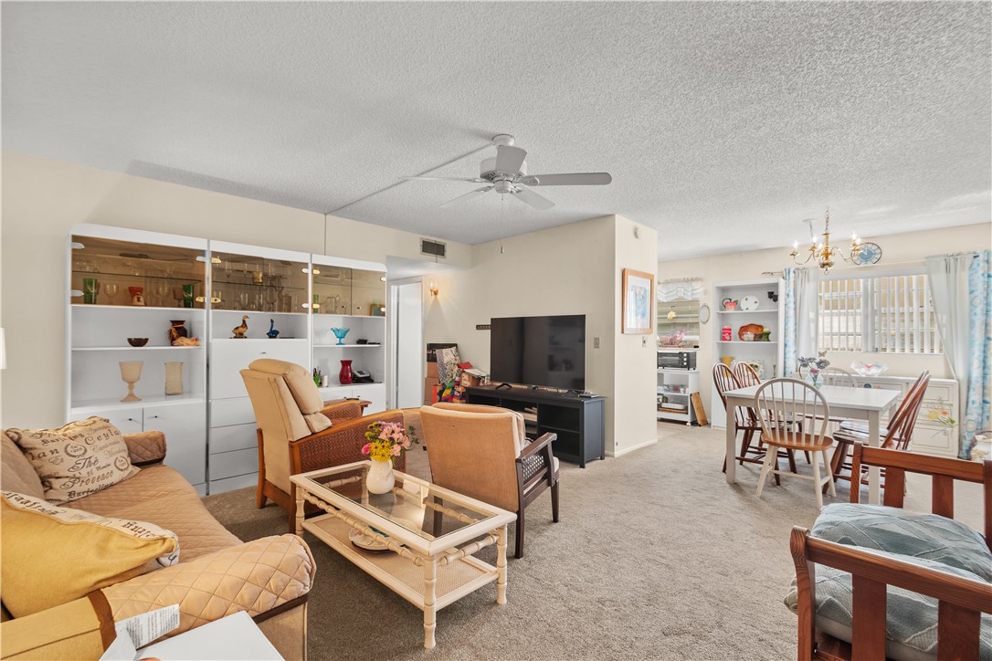 Living area featuring neutral-toned carpet flooring and a ceiling fan