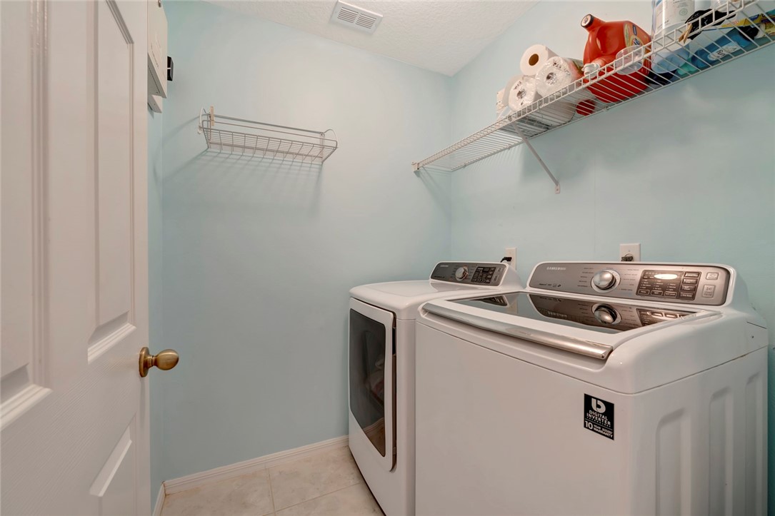 Dedicated laundry room featuring wire shelving, a white paneled door with brass hardware, and tiled flooring
