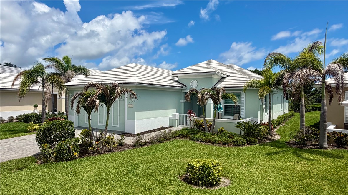 Single-story residence featuring a light blue and white exterior, white tile roof, and a paver driveway