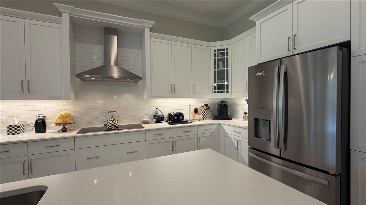 Modern kitchen featuring white shaker cabinetry, stainless steel appliances, a subway tile backsplash, and light-toned countertops