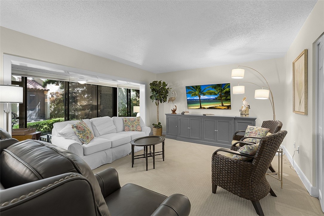 Living area featuring a wide window with dark frames, light-toned wall paint, and recessed lighting