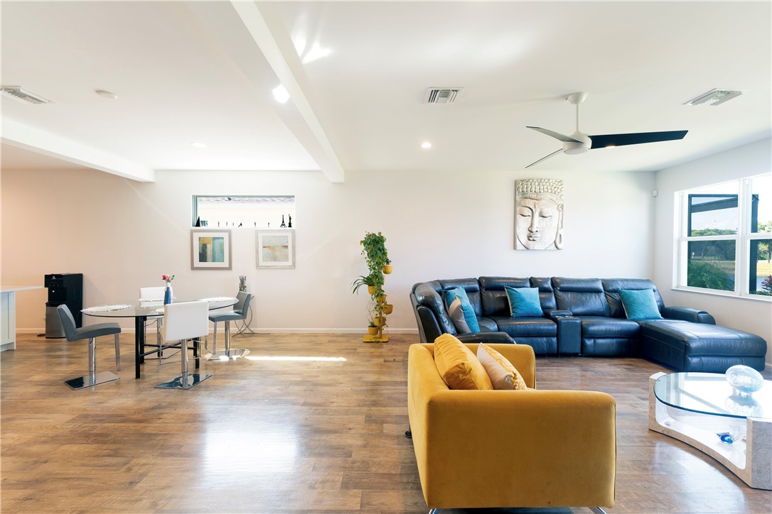 Open-concept living area with wood-finish flooring, a modern ceiling fan, recessed lighting, and large windows