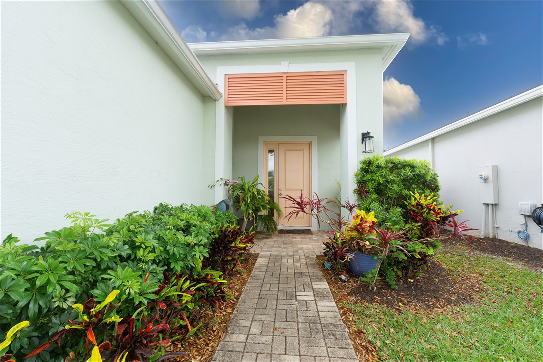 Entryway featuring a light-colored door, decorative wall sconce, and a covered porch area