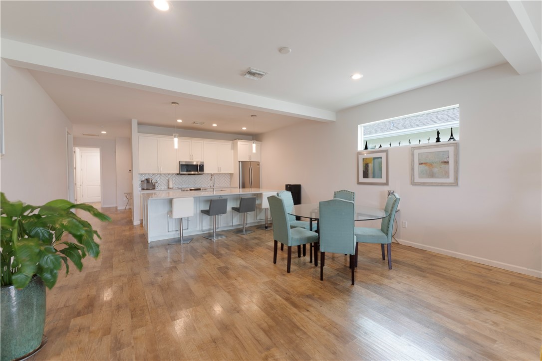 Open-concept living area featuring wood-finish flooring, recessed lighting, and a kitchen with an extended countertop island