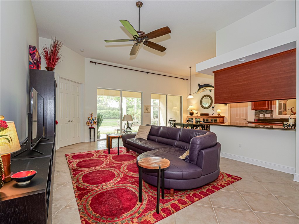 Spacious living area featuring vaulted ceilings, tile flooring, and large sliding glass doors providing access to the exterior
