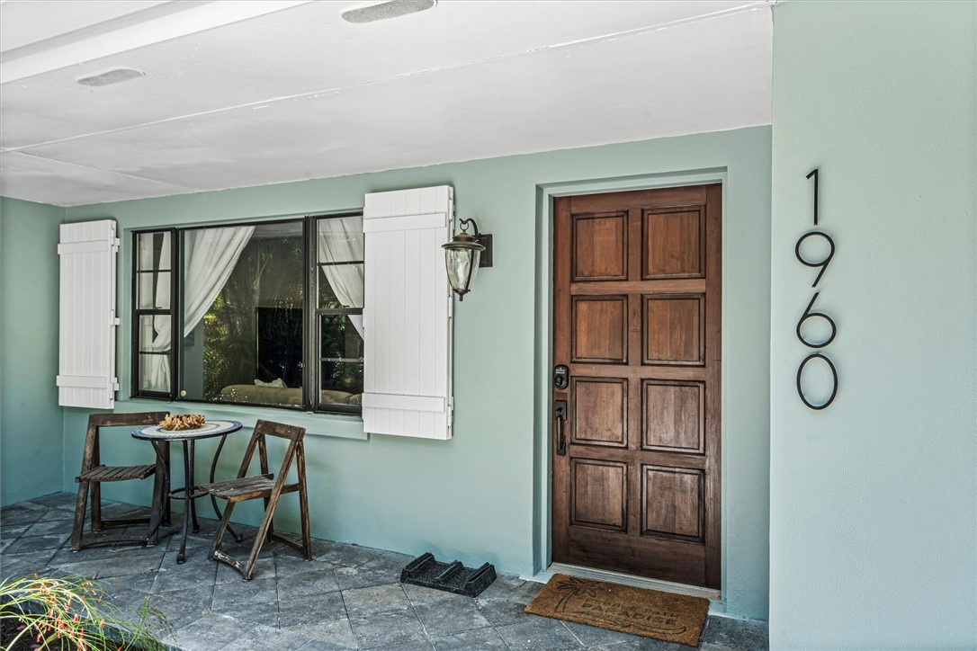 Covered front entry featuring a paneled wood door, with white shutters.