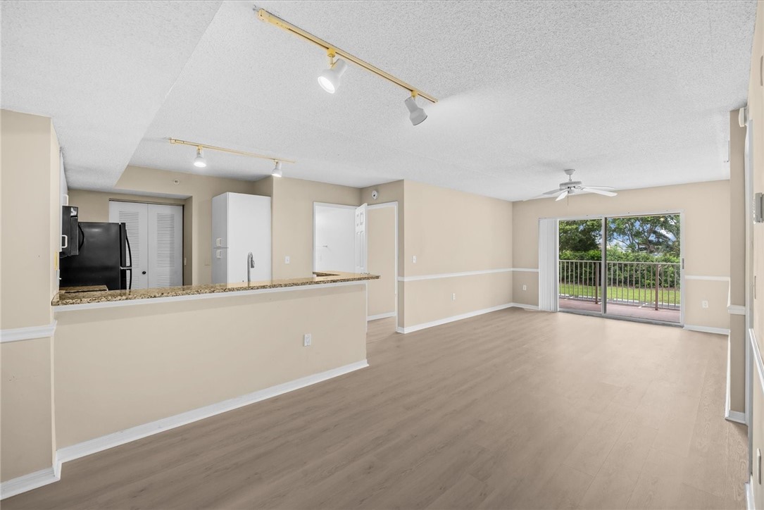 Open-concept living area featuring wood-finish flooring, a contemporary ceiling fan, and track lighting