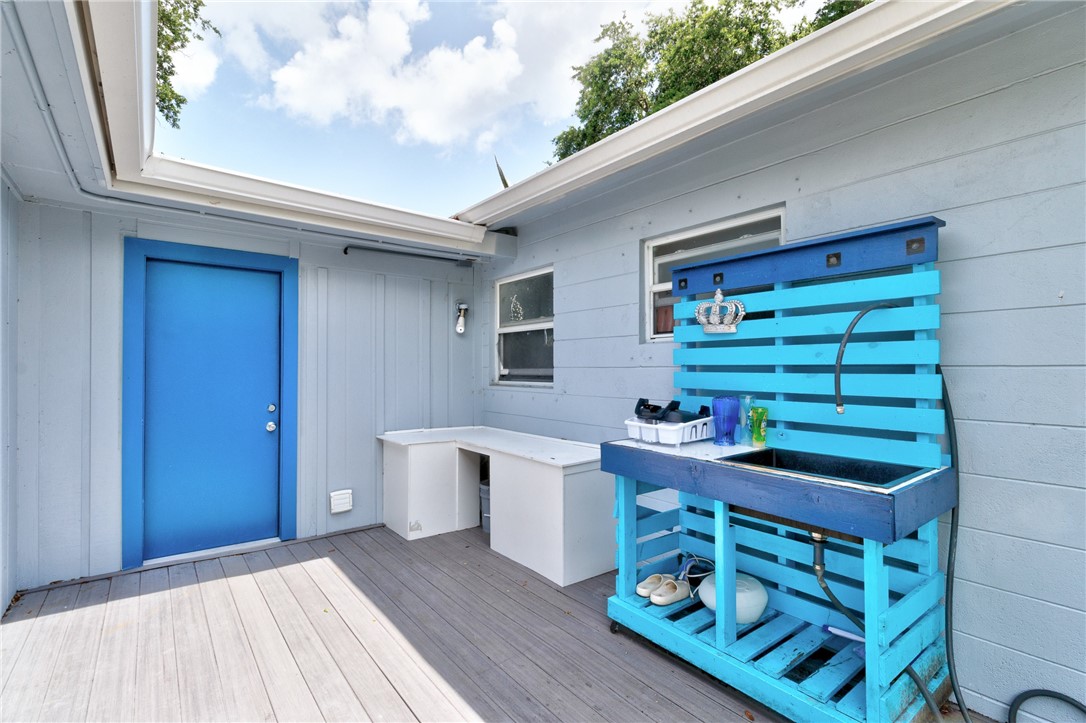 Outdoor decking with a vibrant blue door, coordinating outdoor sink station, built-in counter space, and light blue siding